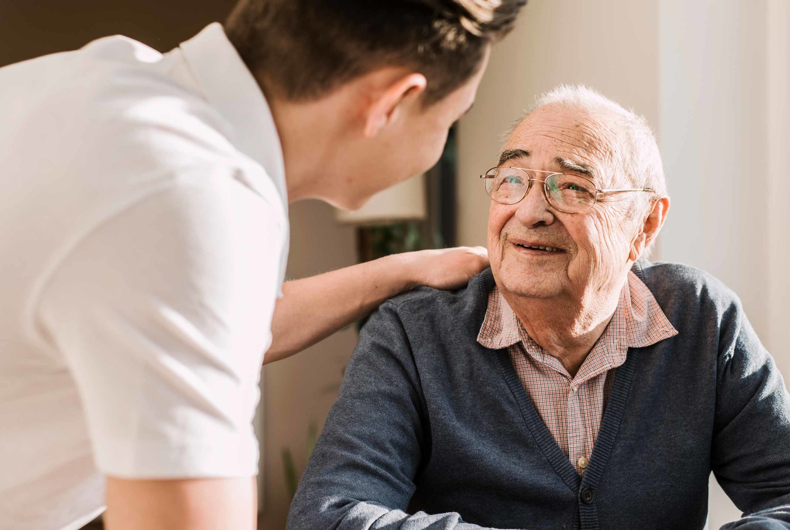 Caregiver comforting elderly man at home