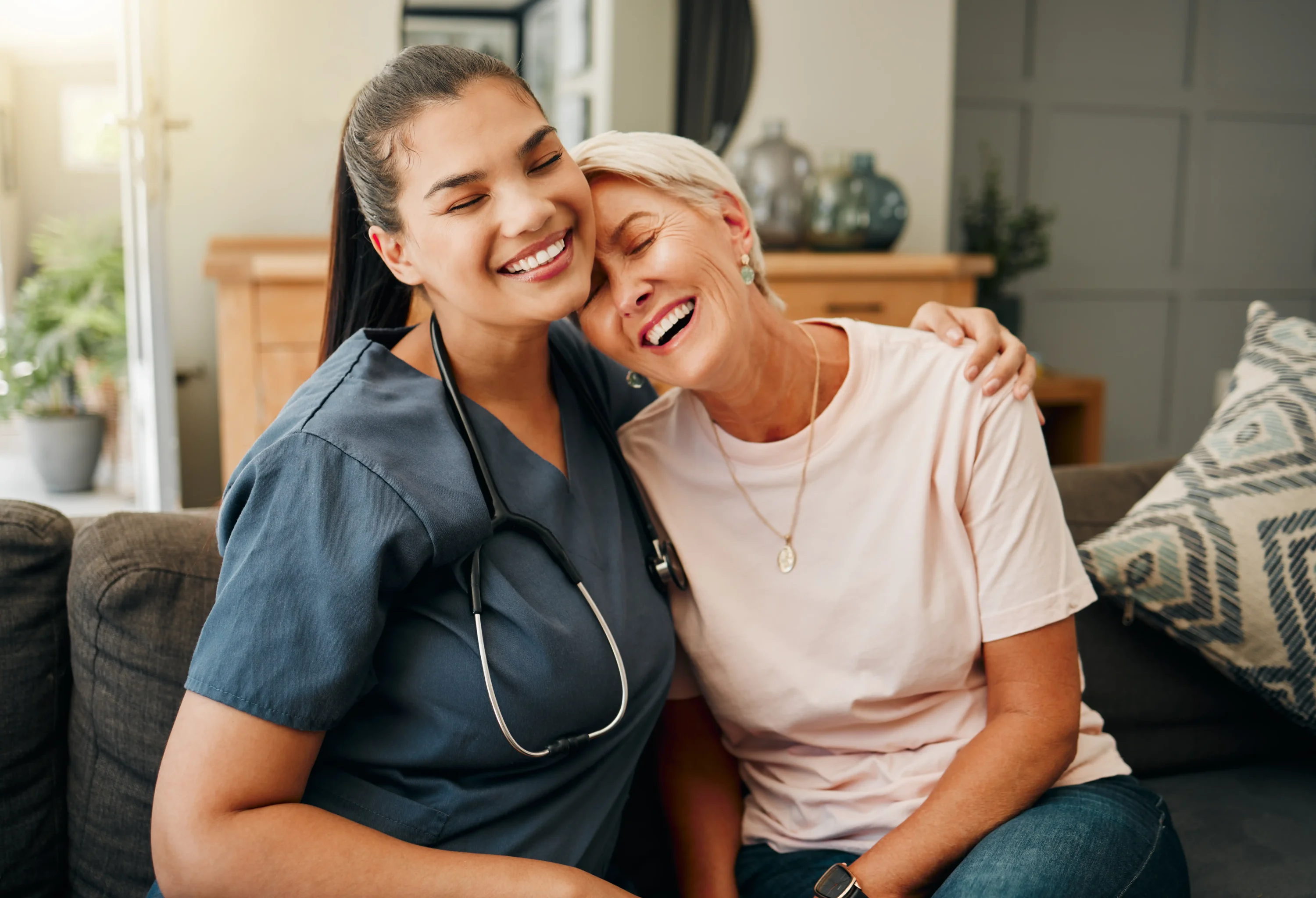 Nurse hugging elderly woman on couch