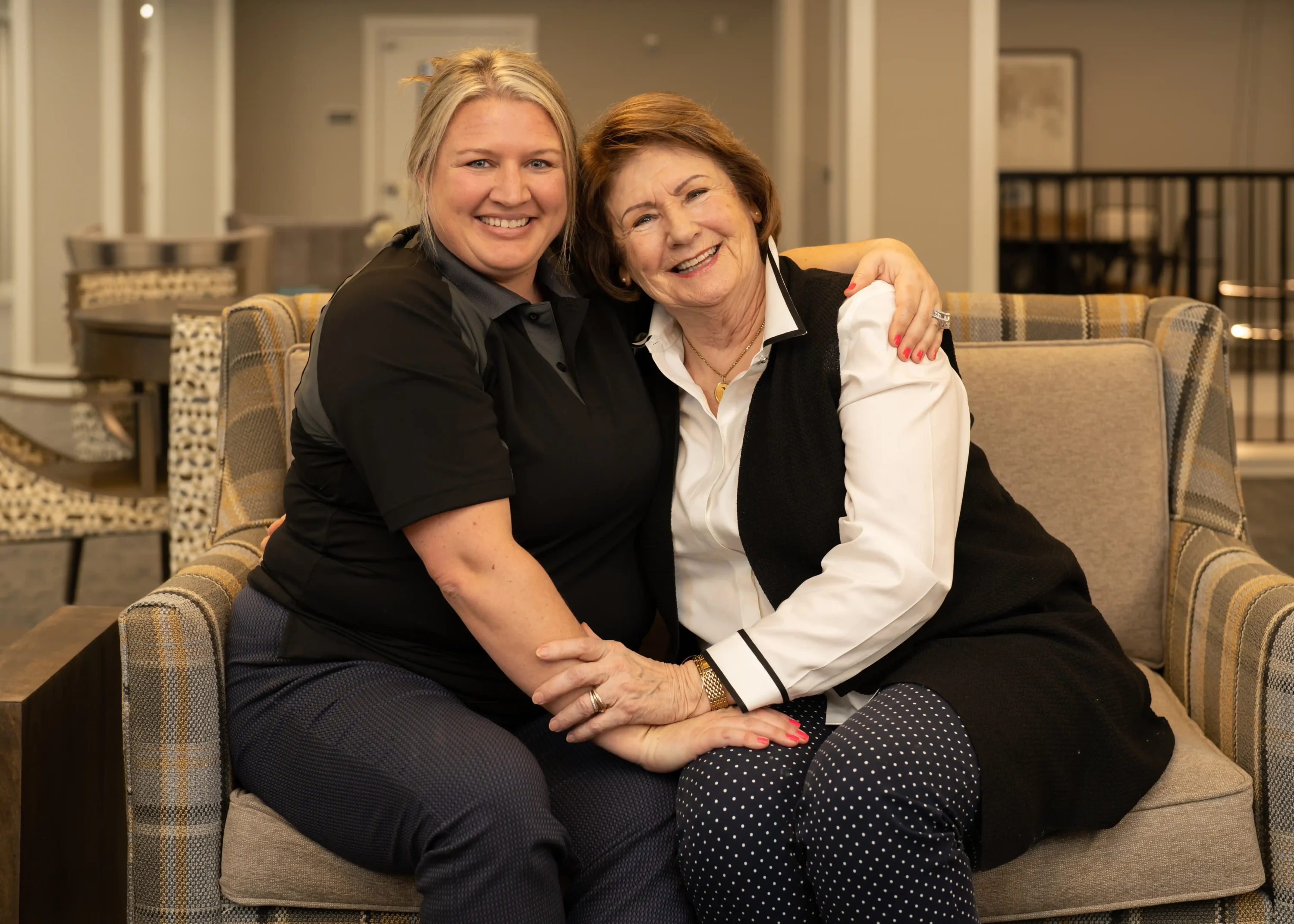 Two women smiling and hugging on couch