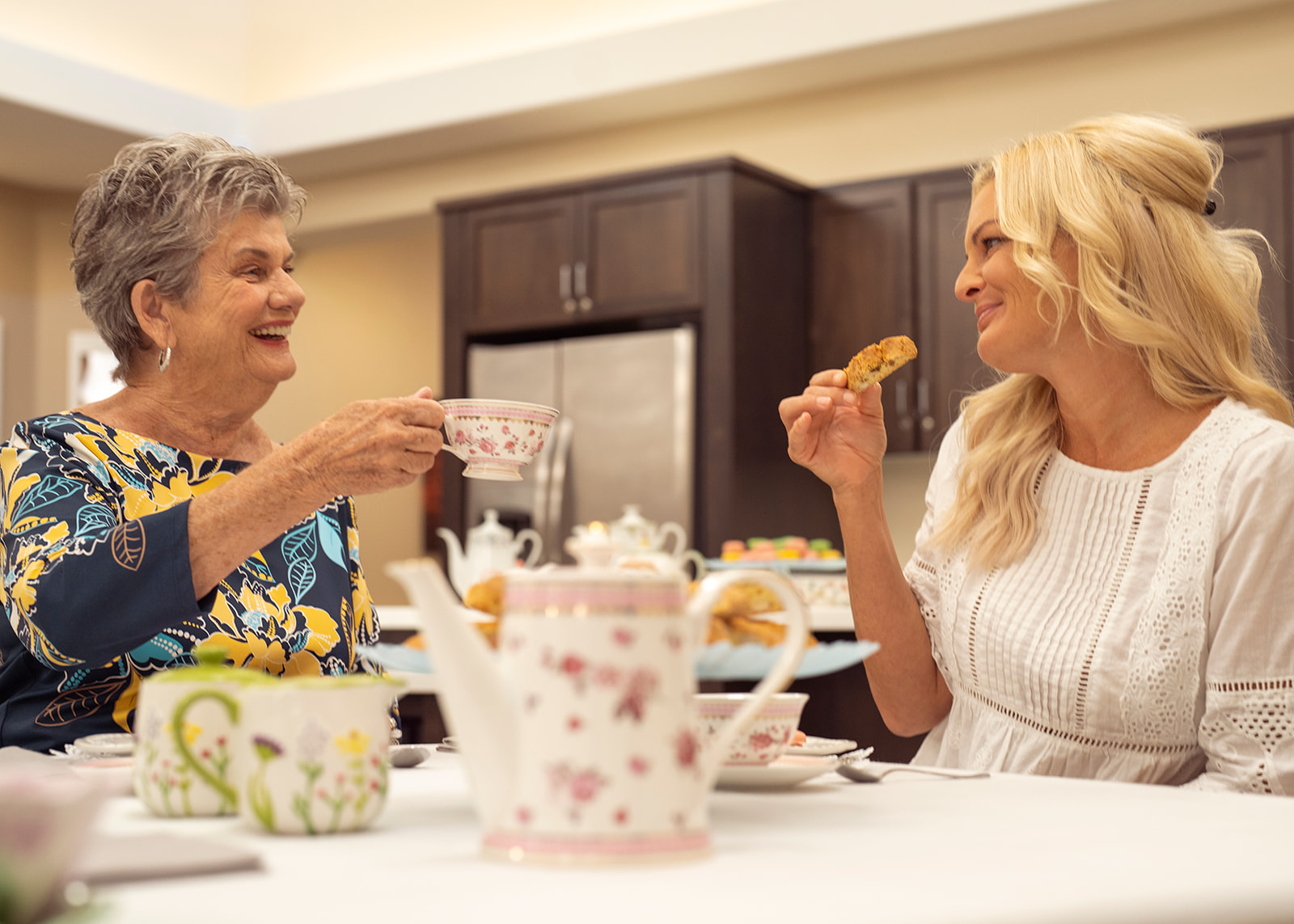 Two women enjoying tea together in kitchen