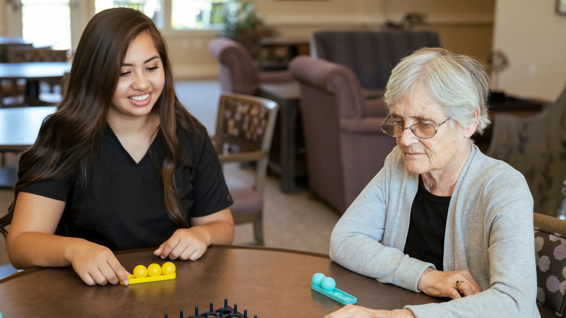 Caregiver and senior woman playing tabletop game