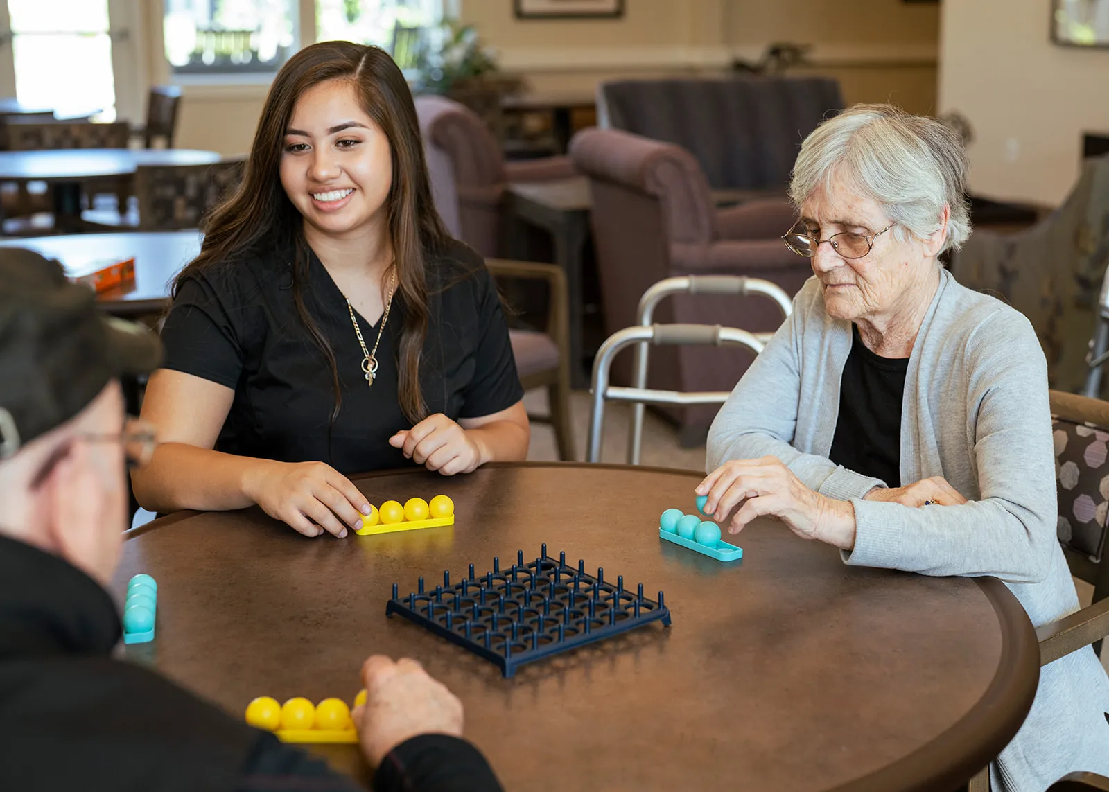 Caregiver playing board game with seniors at table