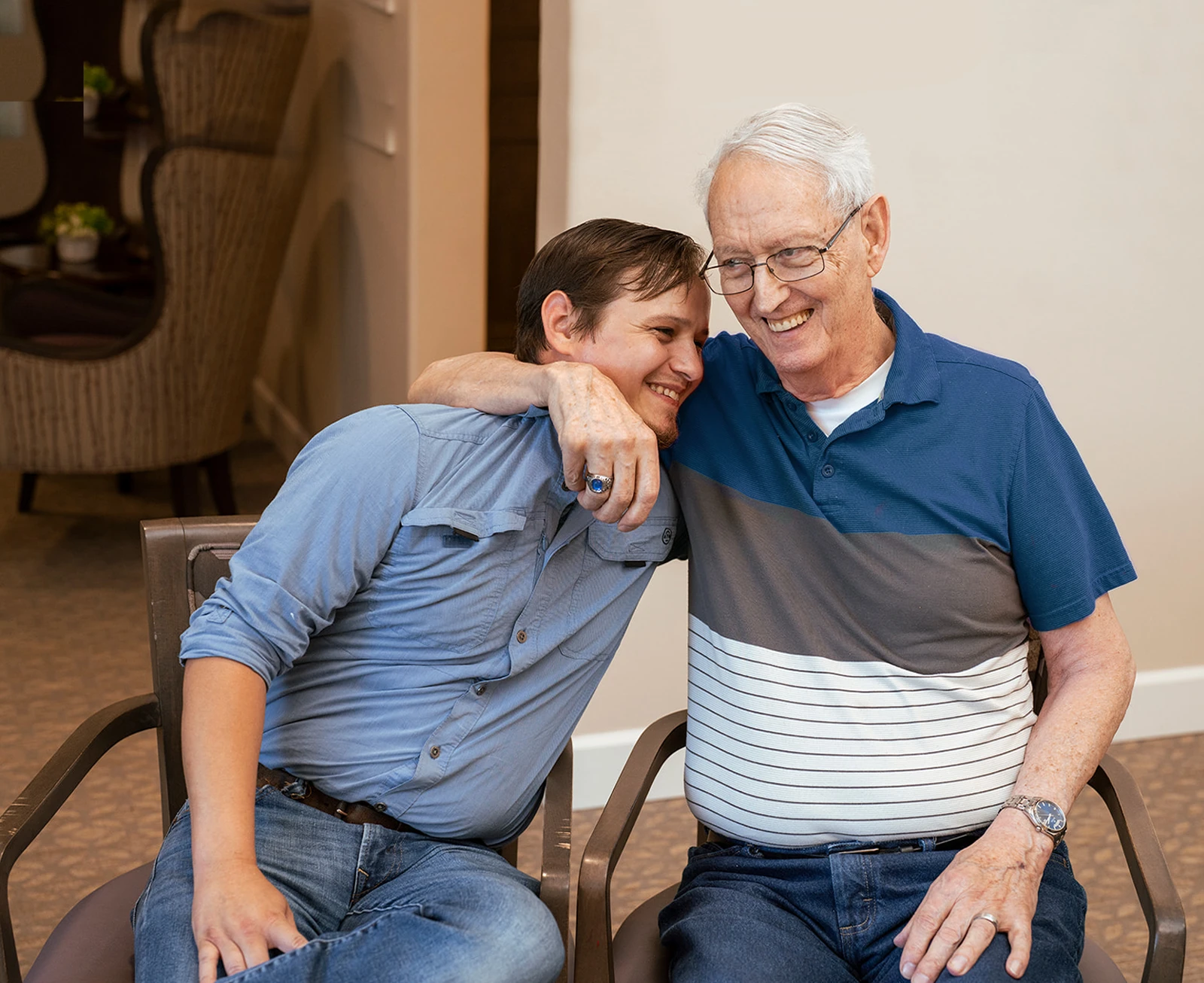 Elderly man hugging younger man indoors