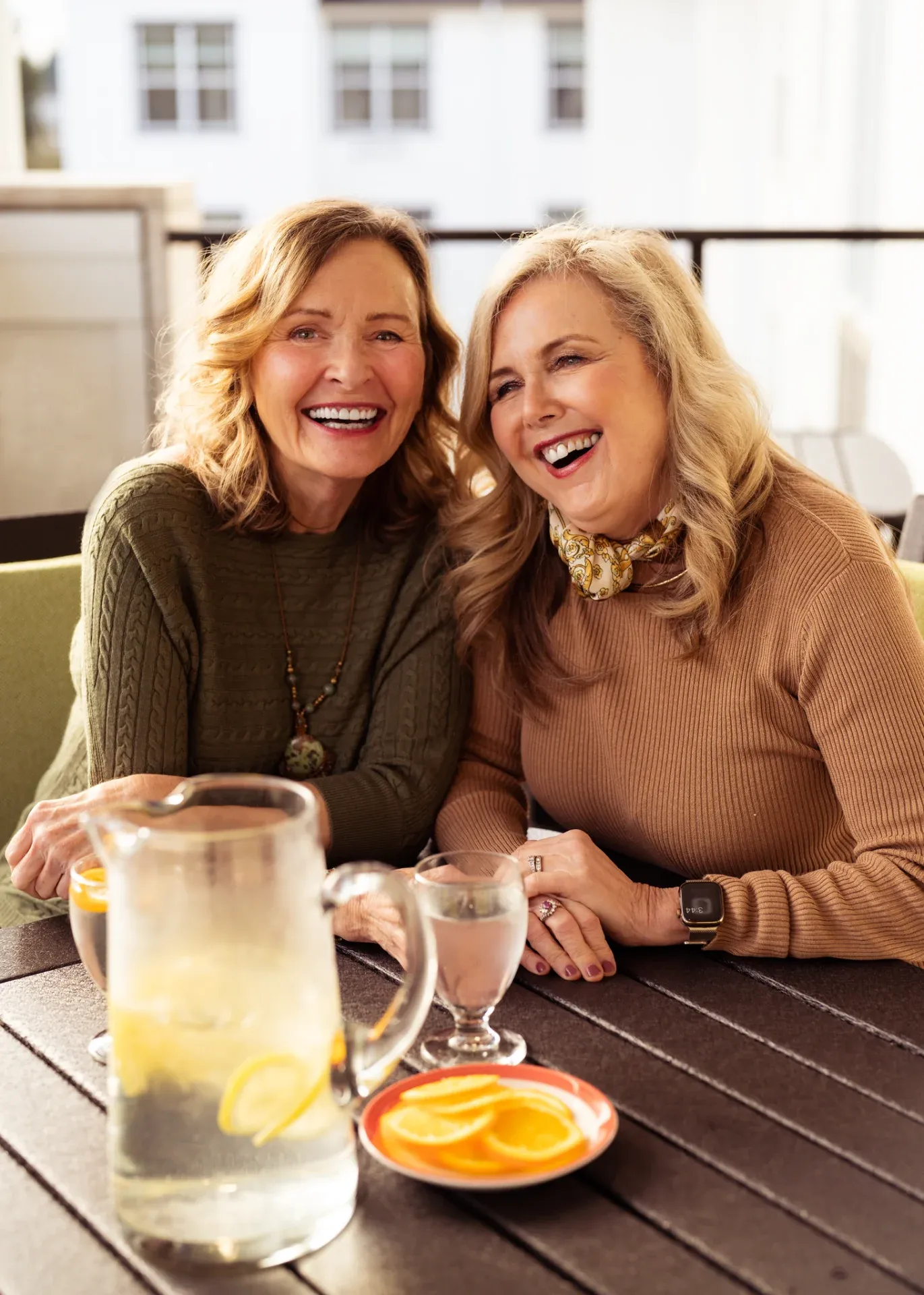 Two women laughing at outdoor café table