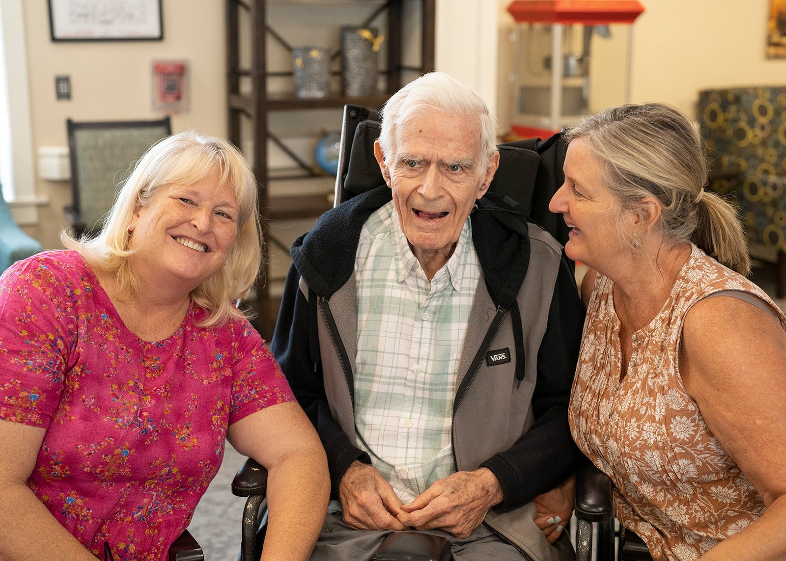 Elderly man in wheelchair with two smiling women