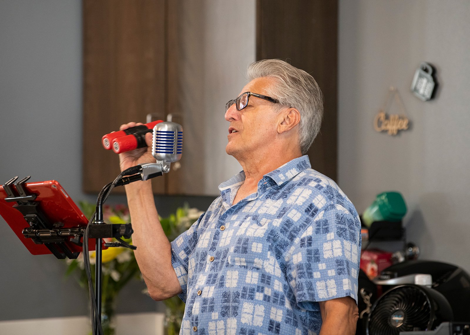 Older man singing into microphone holding maracas