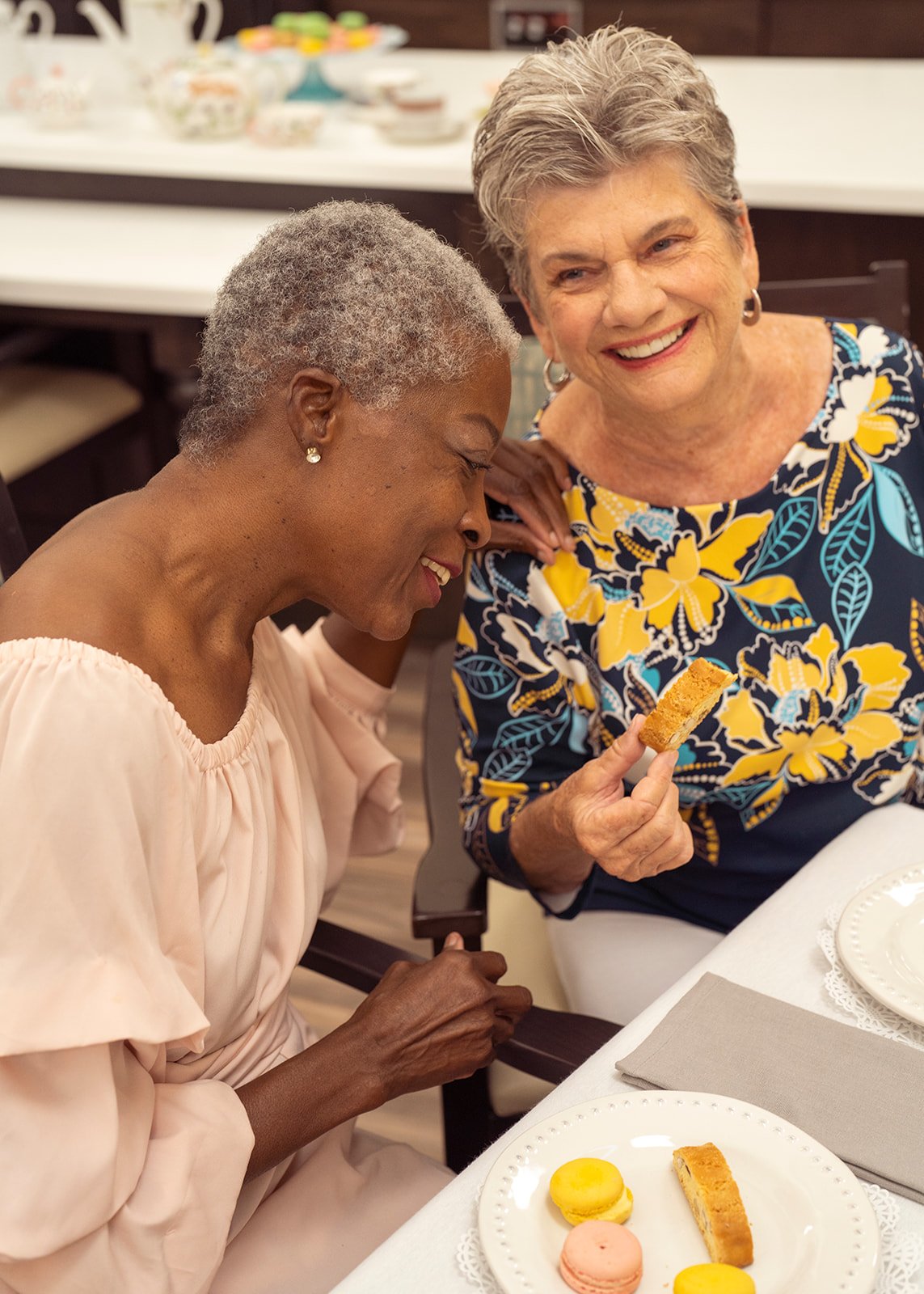 Two elderly women sharing dessert and smiling