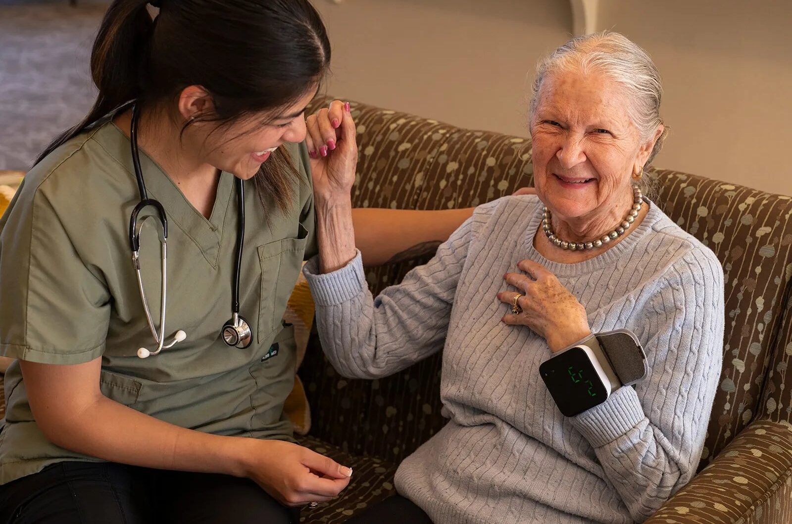 Nurse assisting elderly woman with blood pressure monitor