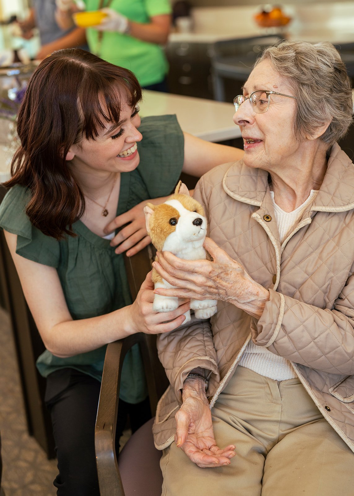 Caregiver and elderly woman holding stuffed dog